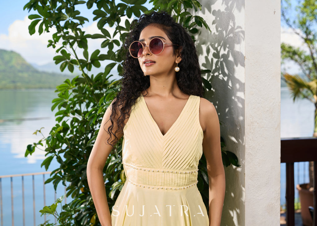 Stylish pastel yellow modal sleeveless dress highlighted with pearl embellishment on the waist.