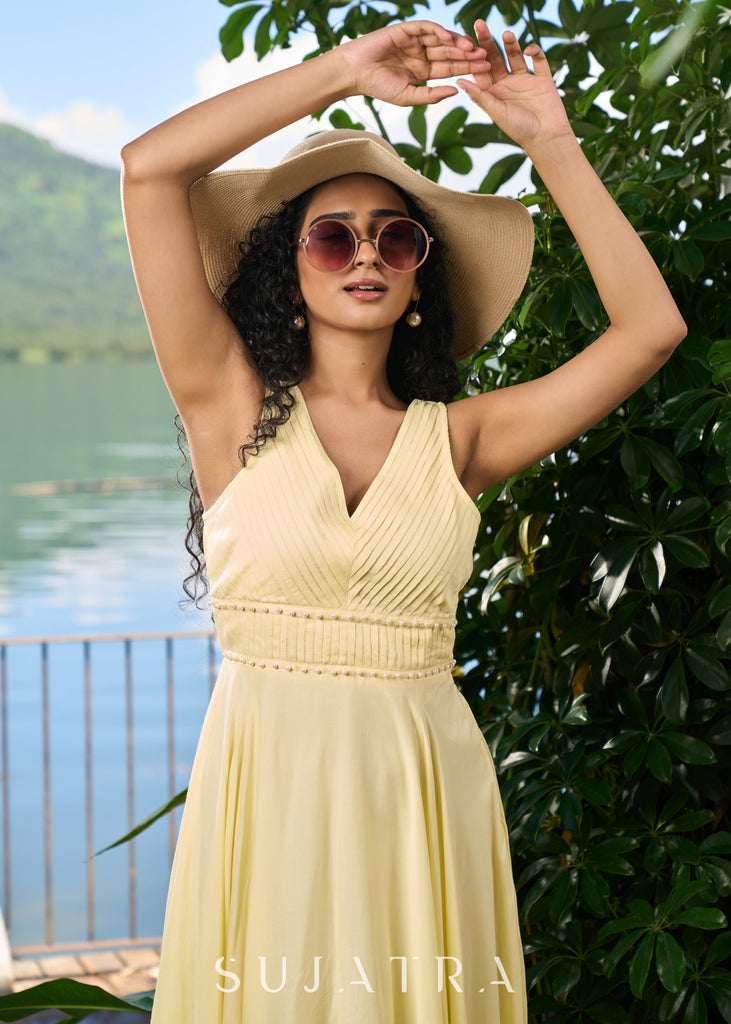 Stylish pastel yellow modal sleeveless dress highlighted with pearl embellishment on the waist.