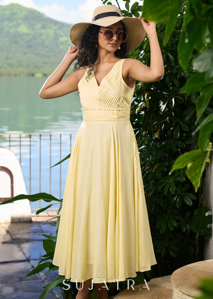 Stylish pastel yellow modal sleeveless dress highlighted with pearl embellishment on the waist.