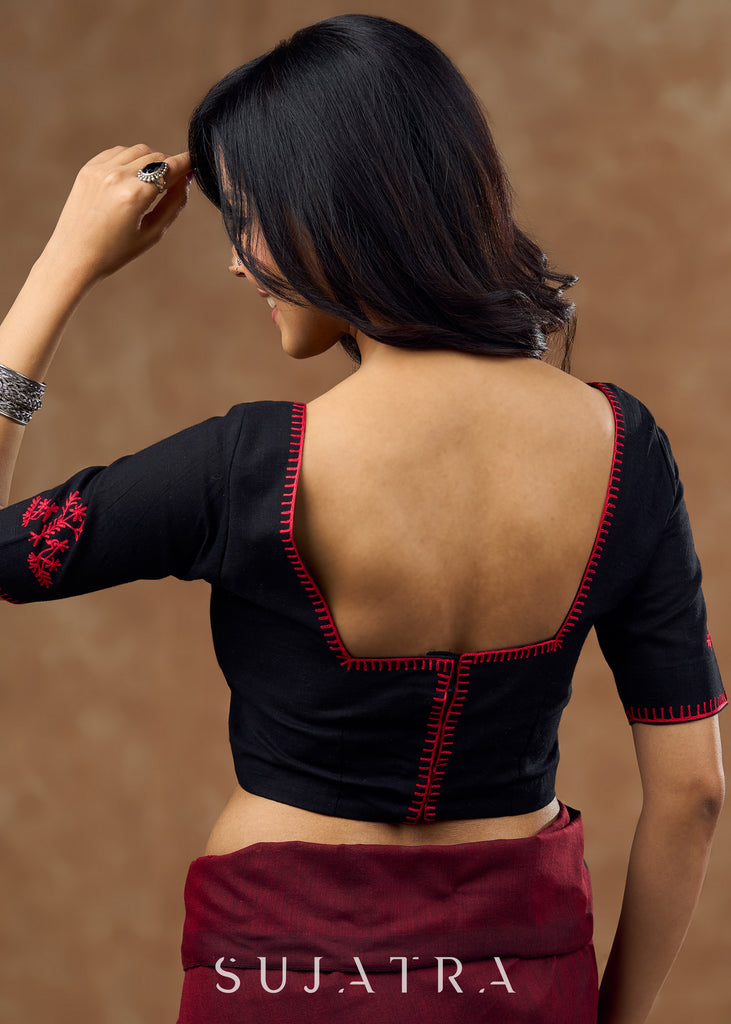 Timeless black blouse elevated by red intricate embroidery , adding a pop of colour .