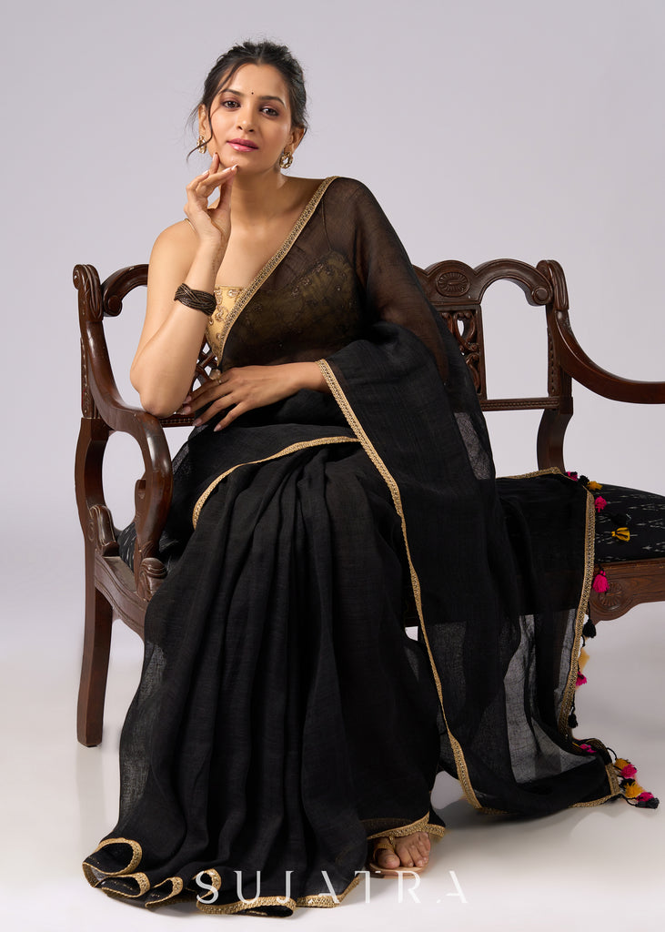 Sophisticated black cotton saree with subtle golden border highlights and pompom