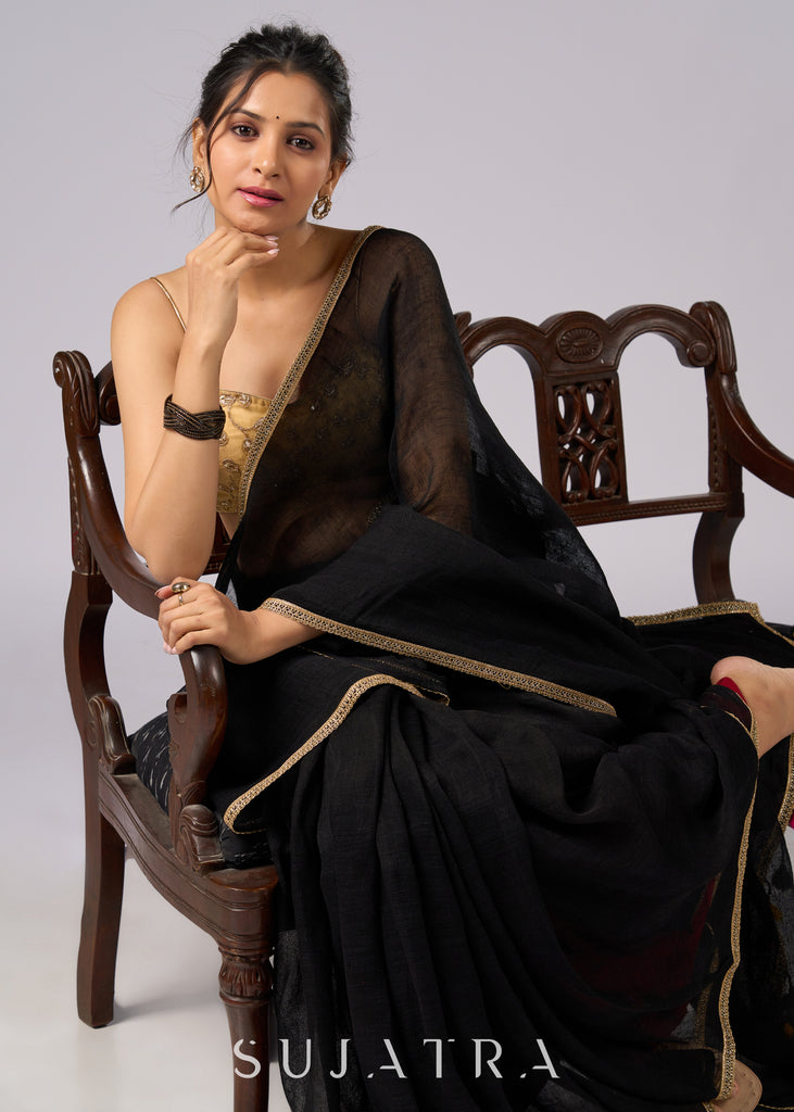 Sophisticated black cotton saree with subtle golden border highlights and pompom