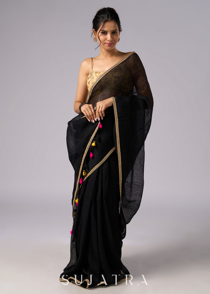 Sophisticated black cotton saree with subtle golden border highlights and pompom