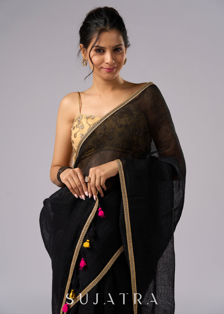 Sophisticated black cotton saree with subtle golden border highlights and pompom