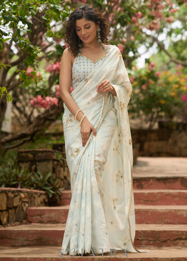 Stylish ice blue floral printed saree highlighted with beautiful golden embroidery