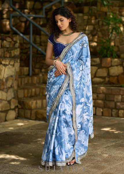 Stylish sky blue floral printed saree highlighted with sequence embroidery & contrast embroidered lace