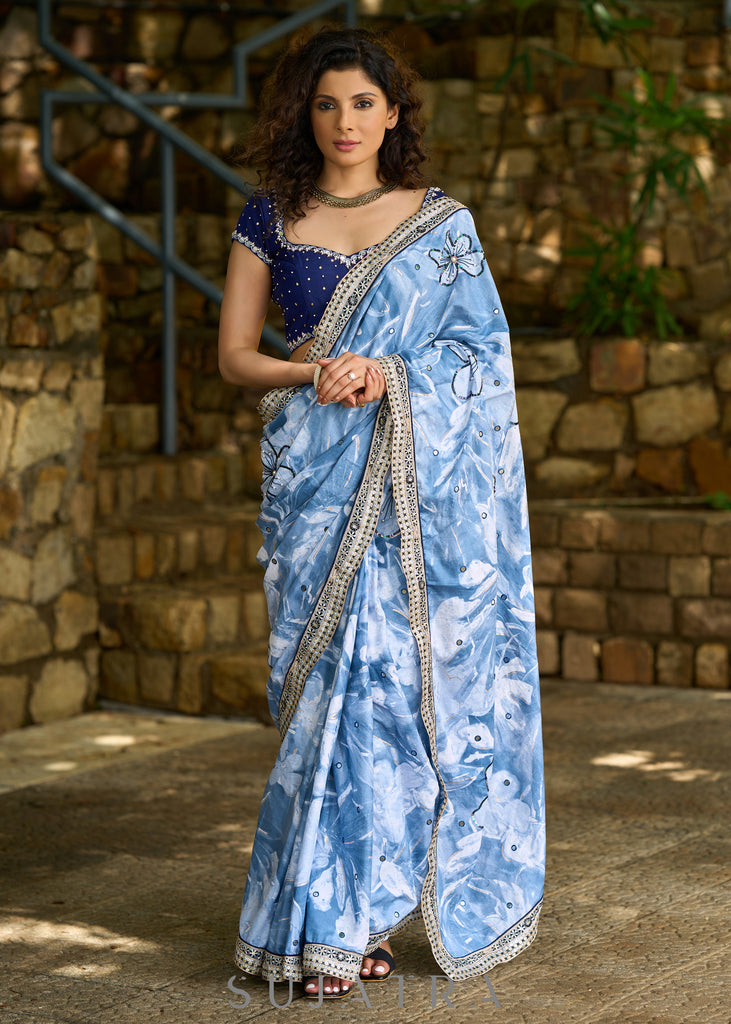 Stylish sky blue floral printed saree highlighted with sequence embroidery & contrast embroidered lace