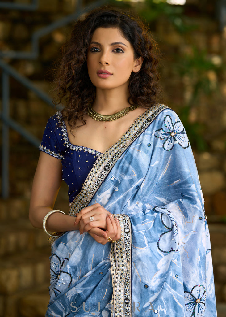 Stylish sky blue floral printed saree highlighted with sequence embroidery & contrast embroidered lace