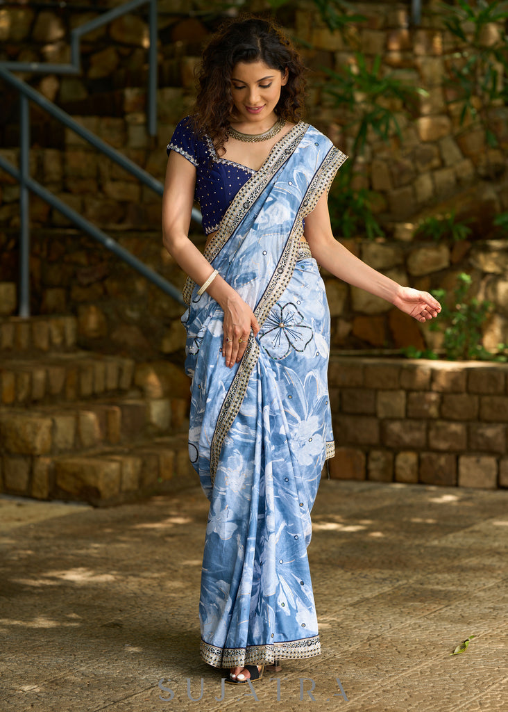 Stylish sky blue floral printed saree highlighted with sequence embroidery & contrast embroidered lace