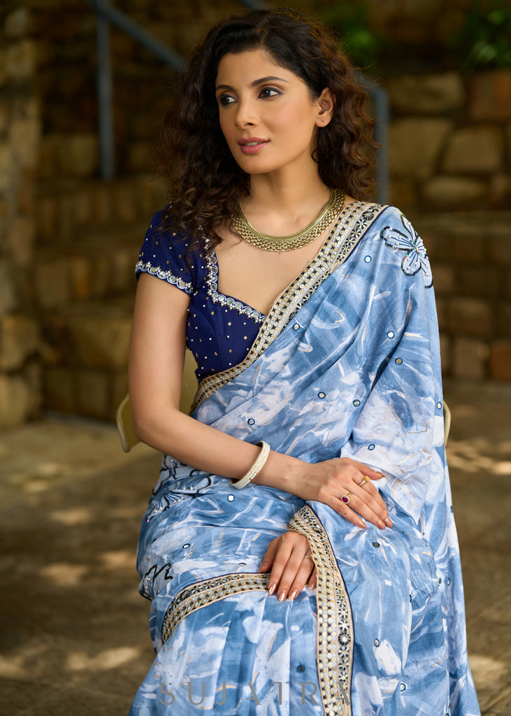 Stylish sky blue floral printed saree highlighted with sequence embroidery & contrast embroidered lace